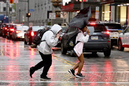 Personas corren en medio de la lluvia en Smithfield St. en Pittsburgh el 29 de abril del 2025. (Sebastian Foltz/Pittsburgh Post-Gazette via AP) (Sebastian Foltz, Pittsburgh Post-Gazette)