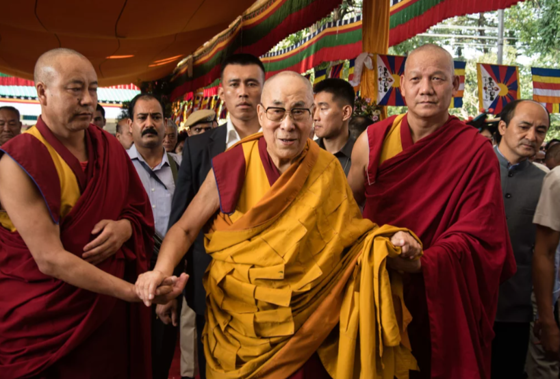 Flanked by Buddhist monks, the Dalai Lama, 84, greets visitors in September at a prayer ceremony at his monastery in Dharamsala, India. NPR